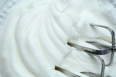 Arka plan olarak çırpılmış yumurta beyazı ve mikser, yakın plan