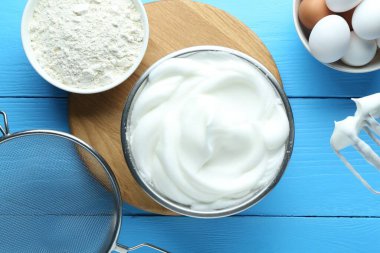 Karıştırıcılı çırpılmış yumurta beyazı ve mavi ahşap masa üzerinde ürünler, düz yatıyordu.