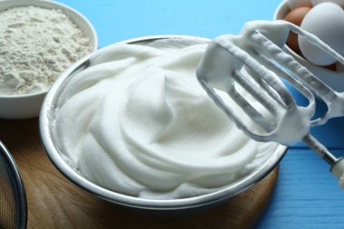 Kavanozda çırpılmış yumurta beyazı ve mavi ahşap masada ürünler, yakın plan.