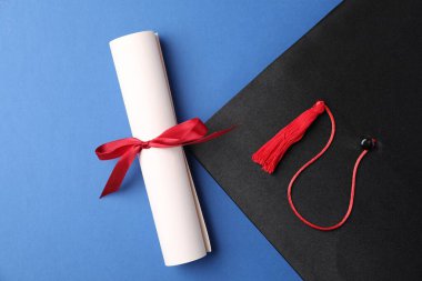 Diploma ve mezuniyet şapkası mavi arka plan, düz yatış