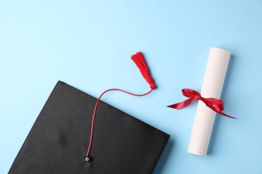 Diploma ve mezuniyet şapkası açık mavi arka plan, düz yatış