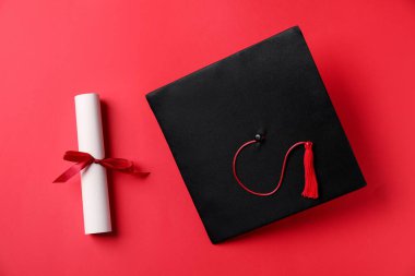 Diploma ve mezuniyet şapkası kırmızı arka plan, düz yatış