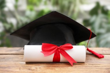 Diploma ve mezuniyet şapkası açık havada ahşap masada, yakın plan.