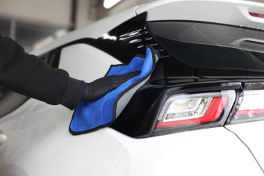 Adam oto yıkamada bez ile araba siliyor, yakın plan.