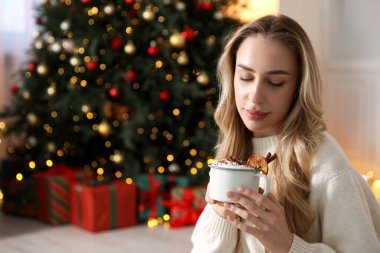 Güzel bir kadın krem şantili, tarçınlı ve portakal dilimli sıcak kakao içiyor. Mesaj için yer var. Noel sezonu