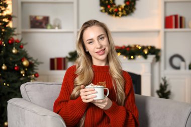 Güzel bir kadın krem şantili, tarçınlı ve portakal dilimli sıcak kakao içiyor. Noel sezonu