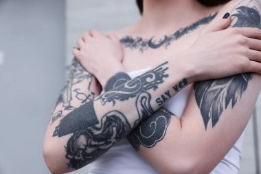 Dövmeleri ve şık kıyafetleri olan genç bir kadın, yakın plan.