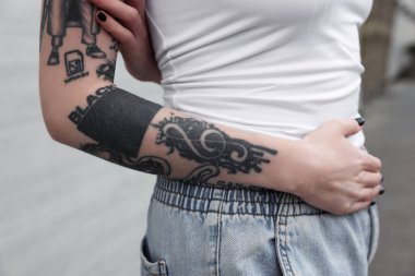 Dövmeleri ve şık kıyafetleri olan genç bir kadın, yakın plan.