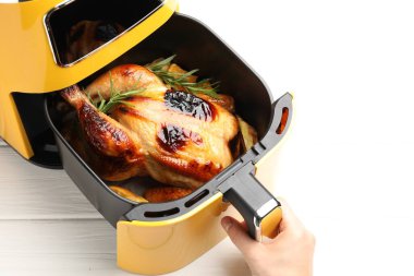 Beyaz ahşap masada tavuk ve sebze pişiren kadın, yakın plan.