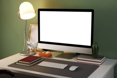 Ofisteki masasında bilgisayar ve gri paspas olan şık bir iş yeri, yakın plan.