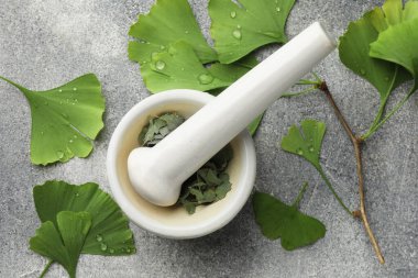 Gri desenli masa üzerinde ıslak ginkgo biloba yaprakları, harç ve tokmak düz yatıyordu.