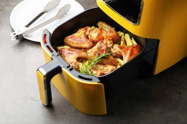 Izgara tavuk kanadı, patates kızartması, biberiye ve maşa, yakın plan.