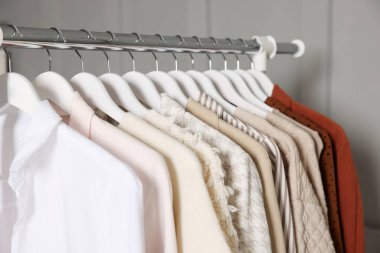 Gri duvarın yanında asılı farklı giysiler, yakın plan.