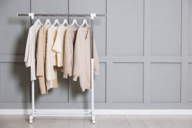 İçerideki gri duvarın yanında farklı kıyafetler asılı. Metin için boşluk