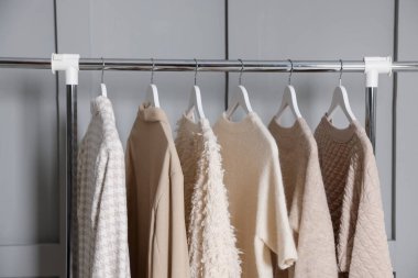 Gri duvarın yanında asılı farklı elbiseler.