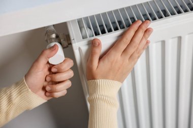 Radyatörün sıcaklığını ayarlayan kadın, yakın plan.
