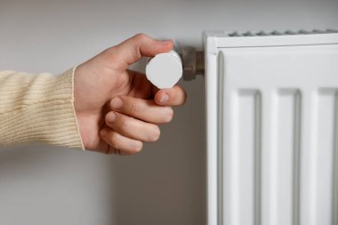 Radyatörün sıcaklığını ayarlayan kadın, yakın plan.
