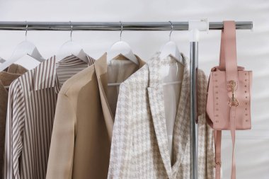 Beyaz duvarın yanında asılı duran farklı şık kıyafetler.