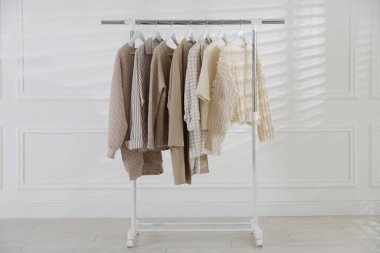 Beyaz duvarın yanında asılı farklı şık kıyafetler.