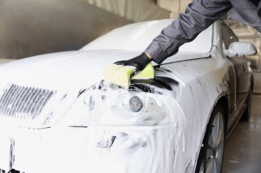 Oto yıkayan adam araba yıkamada süngerle yıkıyor.