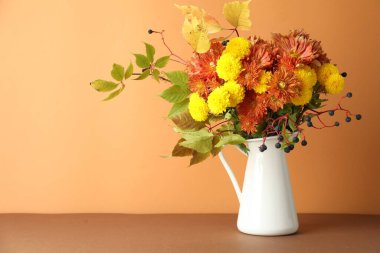 Sonbahar atmosferi. Üzerinde güzel çiçekler ve böğürtlenler olan vazo turuncu arka planda, metin için boşluk