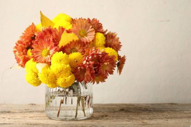 Sonbahar atmosferi. Güzel çiçekli vazo ve ahşap masa üzerinde yapraklar, metin için boşluk