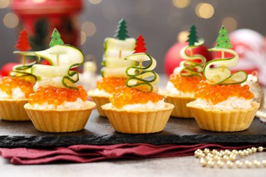 Bulanık ışıklara karşı gri desenli masada lezzetli tartlar, yakın plan. Noel mezesi.