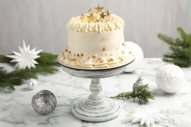 Beyaz mermer masanın üstünde Noel süsü olan lezzetli bir pasta.