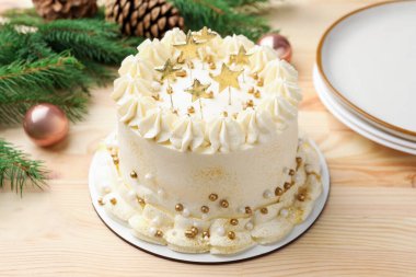 Hafif ahşap masada Noel dekoru olan lezzetli bir pasta, yakın plan.