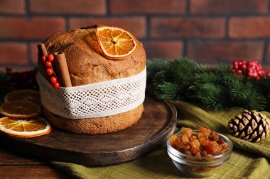 Noel yemeği. Lezzetli Panettone pastası, malzemeler ve ahşap masa üzerindeki şenlikli dekor, yakın plan.