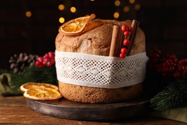 Noel yemeği. Lezzetli Panettone pastası, baharatlar ve ahşap masanın üzerindeki şenlikli dekor. Arka planda bulanık ışıklar, yakın plan. Bokeh etkisi