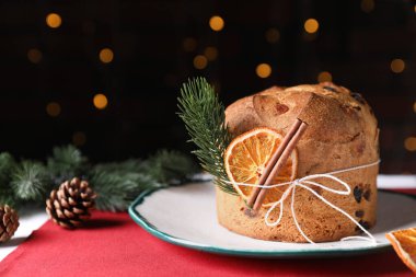Noel yemeği. Lezzetli Panettone pastası, baharatlar ve arka planda arka planda bulanık ışıklarla süslü bir dekor, yakın plan. Bokeh etkisi