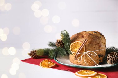 Noel yemeği. Lezzetli Panettone pastası, baharatlar ve arka planda beyaz masa üzerinde bulanık ışıklarla süslü dekor, yazı için yer. Bokeh etkisi