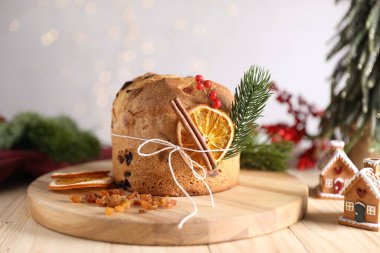 Noel yemeği. Lezzetli Panettone pastası, malzemeler, zencefilli çörekler ve ahşap masa üzerindeki şenlikli dekorlar arka planda bulanık ışıklar, yakın plan. Bokeh etkisi
