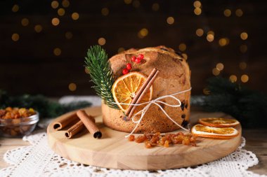 Noel yemeği. Lezzetli Panettone pastası, malzemeler ve ahşap masanın üzerindeki dekoratif dekor arka planda bulanık ışıklar, yakın plan. Bokeh etkisi