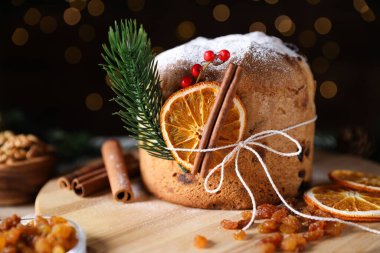 Noel yemeği. Lezzetli Panettone pastası, malzemeler ve arka planda arka planda bulanık ışıklı şenlikli dekor, yakın plan. Bokeh etkisi