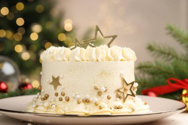 Bulanık ışıklara karşı beyaz masanın üzerinde Noel süsü olan enfes bir pasta.