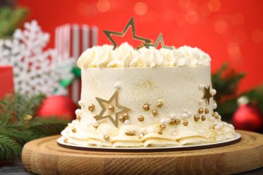 Masanın üzerinde kırmızı arka planlı, bulanık ışıklı, yakın plan Noel süslemeli lezzetli bir pasta.