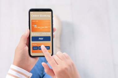 Çevrimiçi ödeme. Bankacılık uygulamasını kapalı mekanda akıllı telefonda kullanan bir kadın.