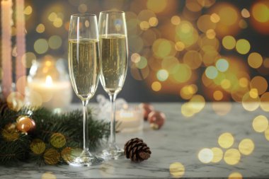 Bardakta köpüklü şarap, şenlikli dekor, ışık. Yeni yıl tebrik kartı.