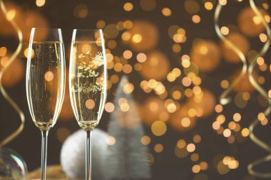 Bardakta köpüklü şarap, şenlikli dekor, ışık. Yeni yıl tebrik kartı.