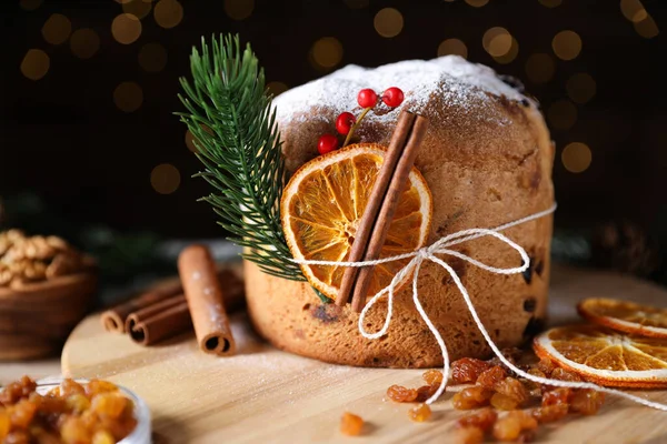 Noel yemeği. Lezzetli Panettone pastası, malzemeler ve arka planda arka planda bulanık ışıklı şenlikli dekor, yakın plan. Bokeh etkisi