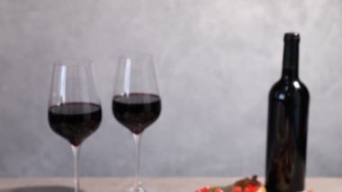 Lezzetli bruschettalar ve gri desenli masada kırmızı şarap, yakın plan. Kamera aşağı iniyor