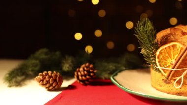 Noel yemeği. Lezzetli Panettone pastası, baharatlar ve arka plandaki şenlikli dekorlar bulanık ışıklarla, kamera sağa dönüyor. Bokeh etkisi
