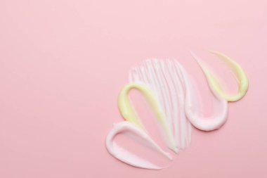 Pembe arka planda farklı kozmetik ürünlerinden örnekler. Metin için boşluk