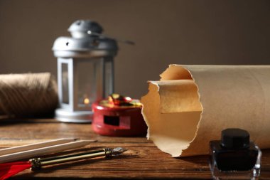 Eski kağıt parşömen, dolmakalem, kalemler ve tahta masa üzerindeki mürekkep hokkası, yakın plan.