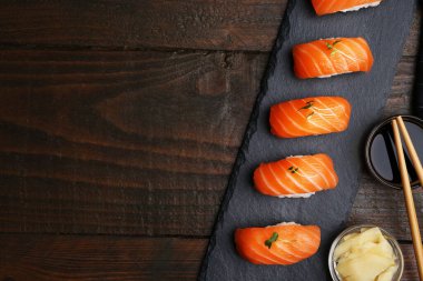 Somonlu lezzetli nigiri suşi, mikroyeşiller, zencefil, soya sosu ve soya çubukları ahşap masada, düz yatak. Metin için boşluk