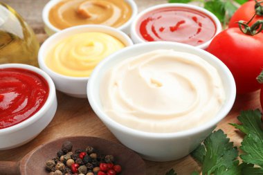 Tabaklardaki farklı soslar ve ahşap masadaki malzemeler, yakın plan.