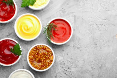 Tabaklardaki farklı soslar ve gri desenli masa üzerindeki bitkiler düz. Metin için boşluk