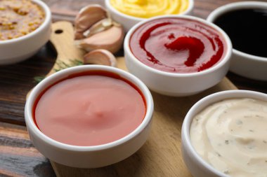 Tabaklardaki farklı soslar ve ahşap masadaki malzemeler, yakın plan.